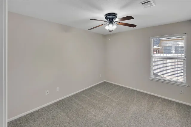an empty room with a chandelier fan and windows
