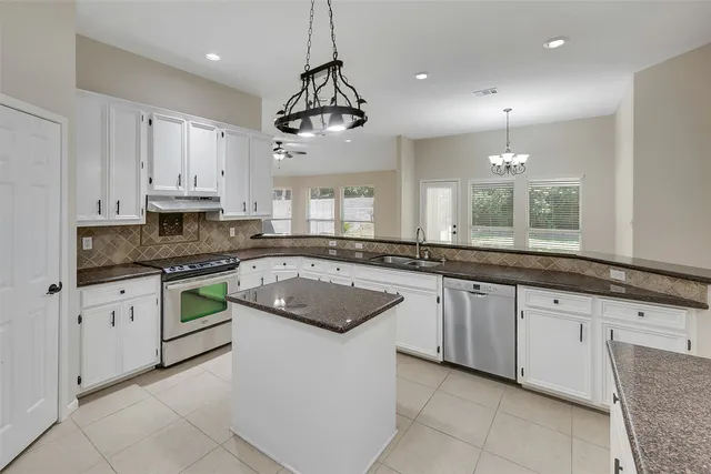 a large kitchen with granite countertop a sink a counter space appliances and cabinets