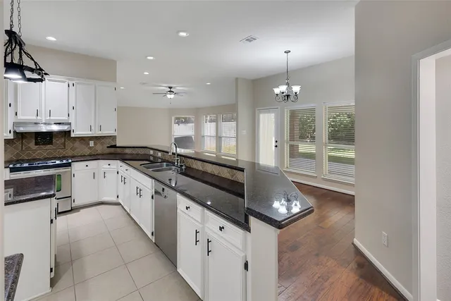 a large kitchen with granite countertop a stove a sink dishwasher and a refrigerator with wooden floor