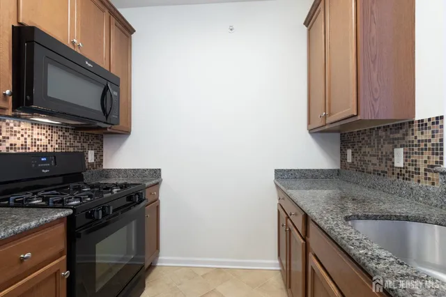 a kitchen with granite countertop stainless steel appliances a sink dishwasher with wooden cabinets and chandelier
