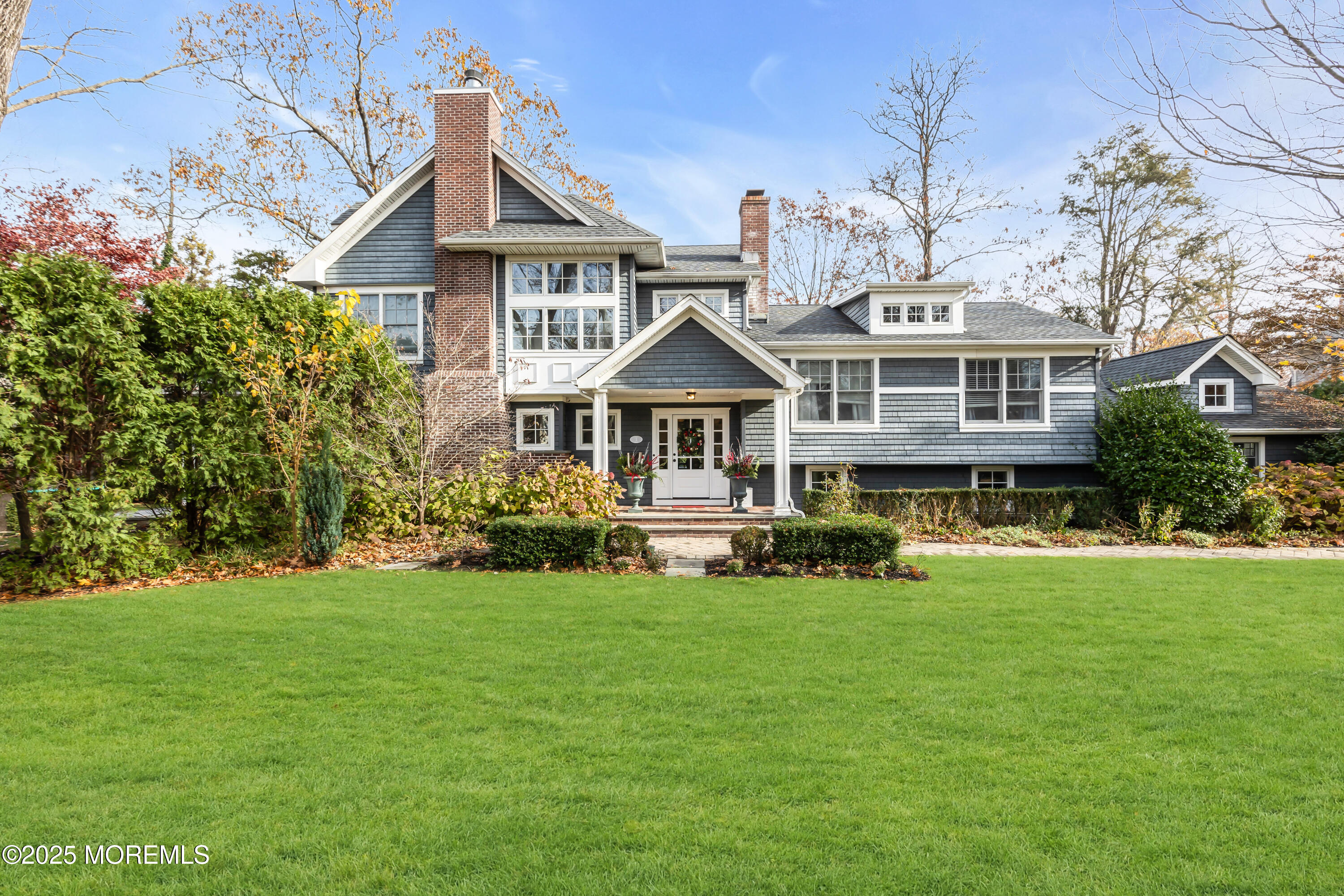 a front view of a house with a garden and trees