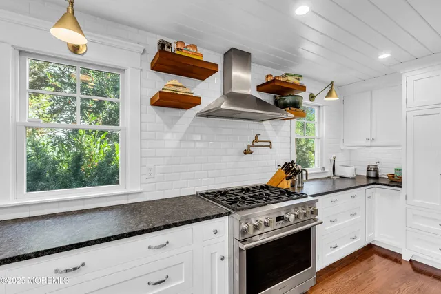 a kitchen with stainless steel appliances granite countertop a sink a stove and a wooden floors