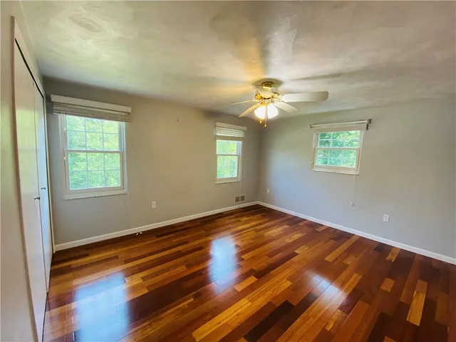 a view of empty room with window and wooden floor