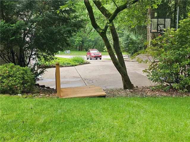 a white bench sitting in the grass near a tree