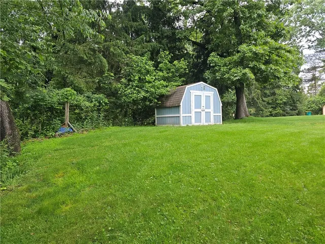 a view of a tiny house with a big yard and large trees