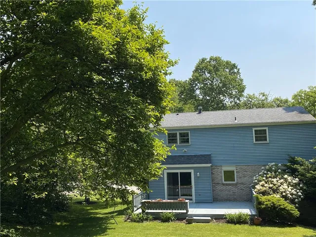 a front view of a house with a garden and trees