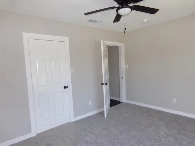 a view of an empty room and chandelier fan