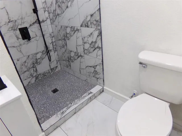 a bathroom with a granite countertop sink a toilet and shower