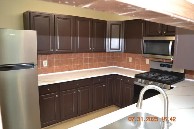 a kitchen with stainless steel appliances granite countertop a refrigerator and a sink