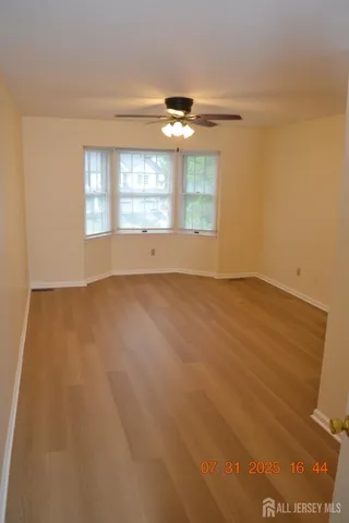 an empty room with windows and ceiling fan