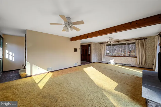 a view of an empty room with a window and a kitchen