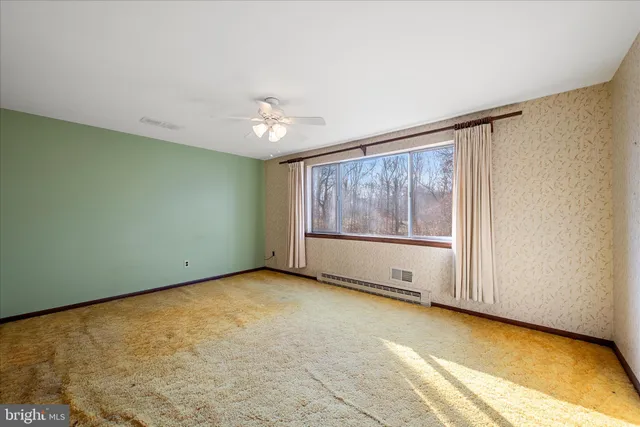 a view of empty room with wooden floor and ceiling fan