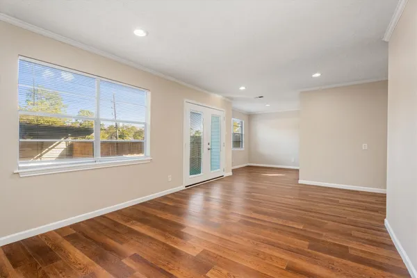 a view of an empty room with wooden floor and a window
