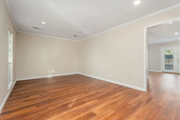 a view of an empty room with wooden floor and a window