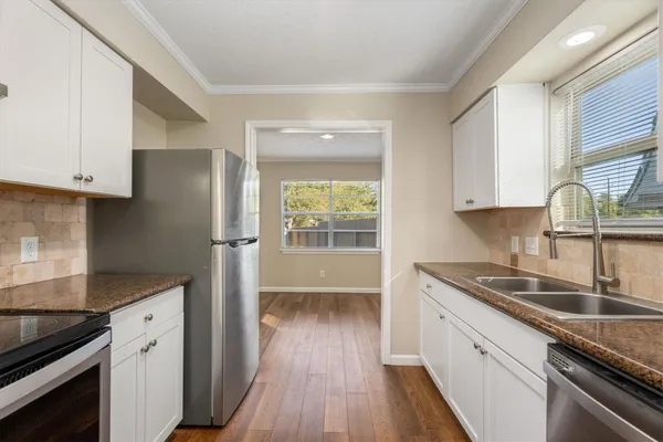 a kitchen with granite countertop stainless steel appliances a sink window and cabinets