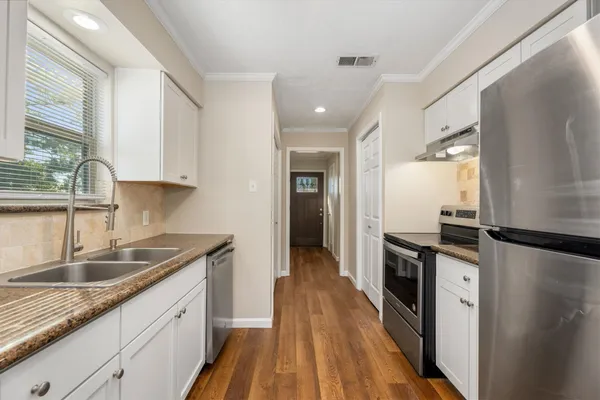 a kitchen with granite countertop a sink stove and refrigerator