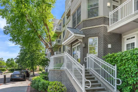 a view of a brick house with large windows and a flower plants with wooden fence