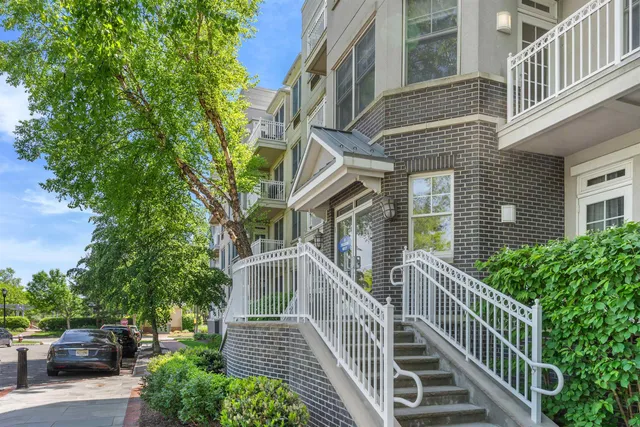 a view of a brick house with large windows and a flower plants with wooden fence