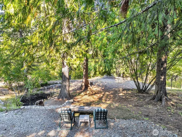 a view of a backyard with table and chairs and a tree