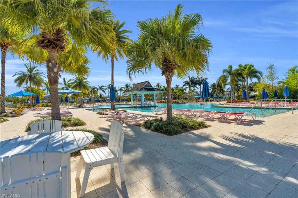 8937 Calypso Court Naples, FL 34113 - Photo 37 of 43 a view of a swimming pool with a lawn chair and palm trees