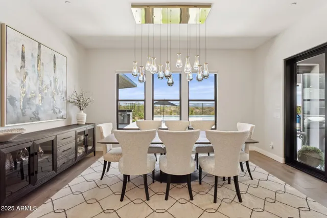 a view of a dining room with furniture a chandelier and large window