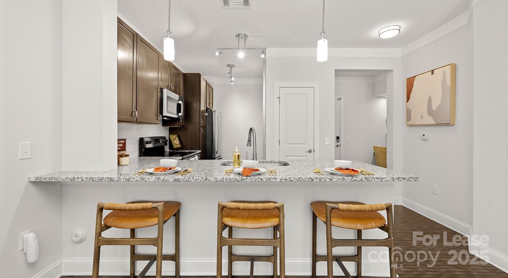 10624 Parrish Street, Unit A1 Matthews, NC 28105 - Photo 35 of 42 a kitchen with stainless steel appliances kitchen island granite countertop a dining table chairs and sink