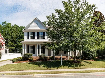 a front view of a house with trees and plants