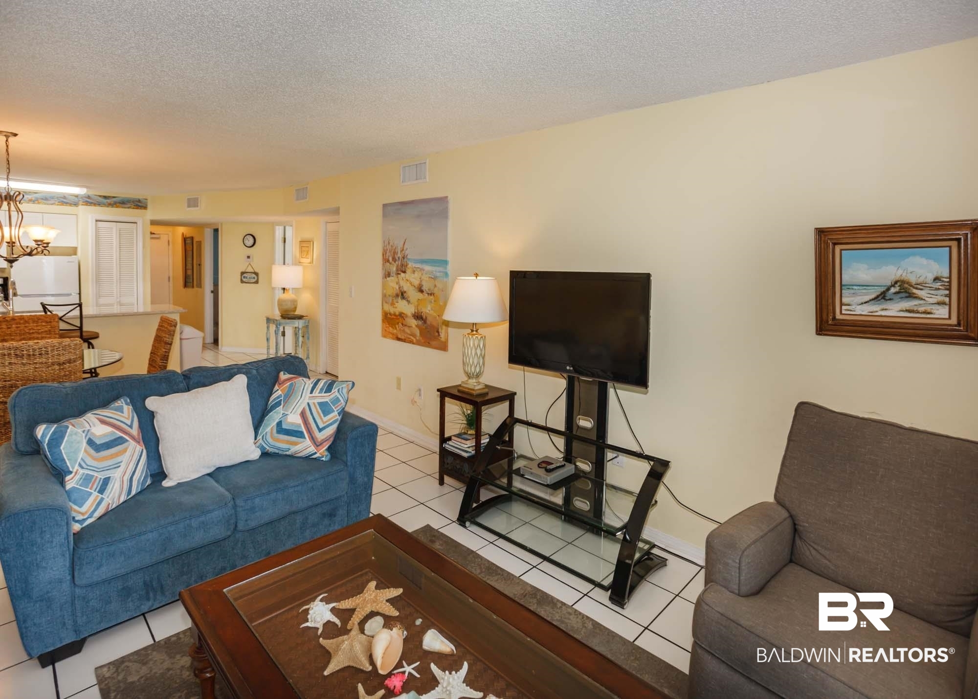 645 Plantation Road, Unit 6311 Gulf Shores, AL 36542 - Photo 30 of 43 Living room featuring light tile patterned floors, a chandelier, a textured ceiling, and baseboards