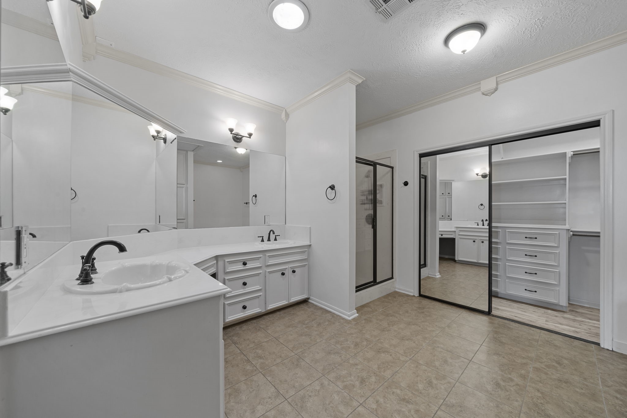 169 April Cove Montgomery, TX 77356 - Photo 13 of 39 WOW! Spacious and beautifully appointed primary bathroom, featuring tile flooring, double sinks with vanity area, vanity lights, recessed lighting, beautiful white cabinetry, and a HUGE walk-in closet with built ins!
