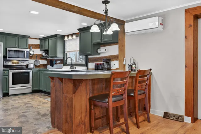a kitchen with stainless steel appliances granite countertop a table chairs and a refrigerator