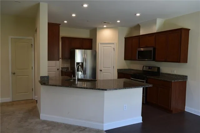 a kitchen with kitchen island granite countertop stainless steel appliances a refrigerator a stove a sink and a refrigerator