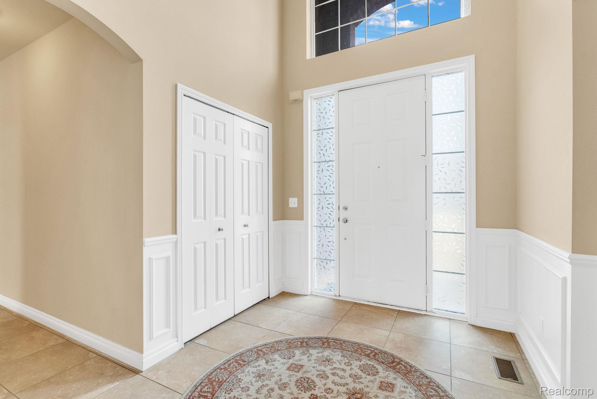 4122 Hawks Nest Road Utica, MI 48317 - Photo 16 of 74 Entrance foyer with a wainscoted wall, light tile patterned flooring, a decorative wall, arched walkways, and a high ceiling