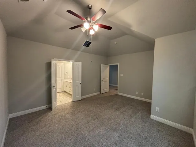 an empty room with windows and fan
