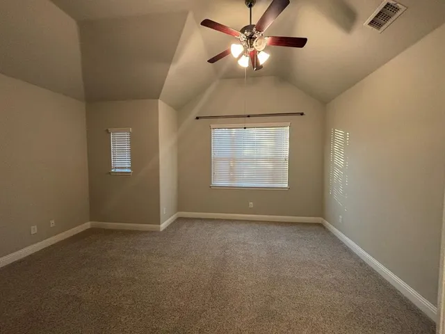 an empty room with chandelier fan and windows