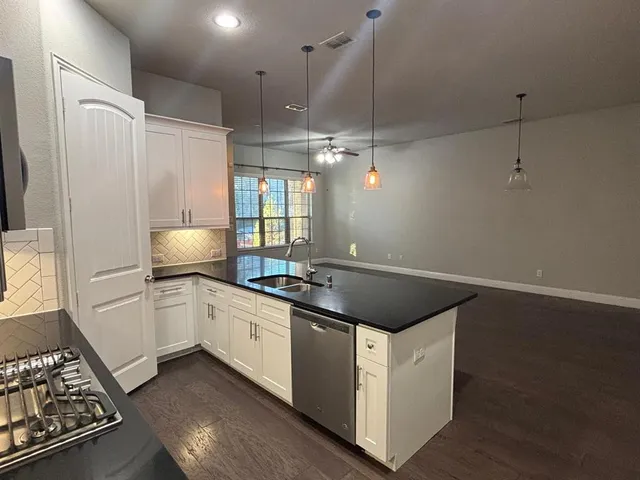 a kitchen with kitchen island granite countertop a sink a refrigerator and a stove