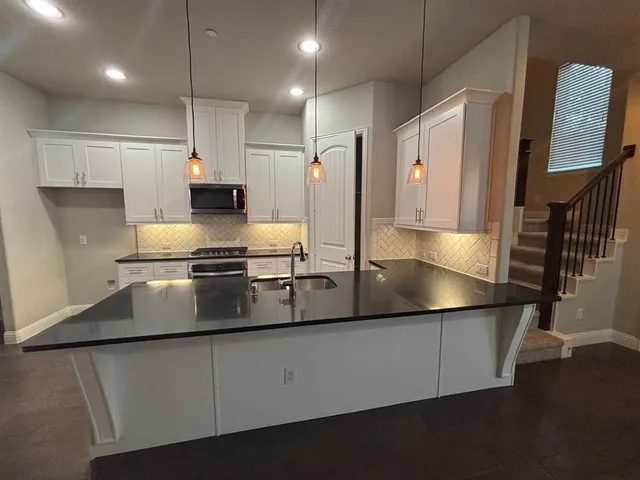 a kitchen that has a lot of cabinets and wooden floor