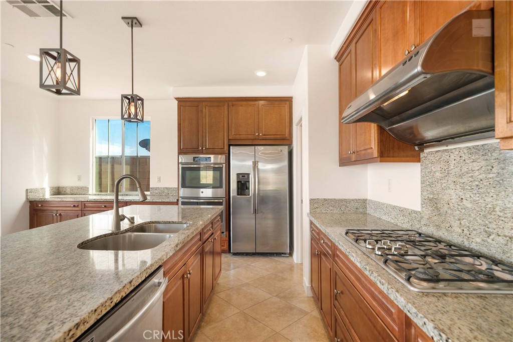 13296 Joliet Drive Rancho Cucamonga, CA 91739 - Photo 12 of 69 a kitchen with kitchen island granite countertop a sink stove and refrigerator