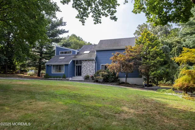 a view of a big house with a big yard and large trees