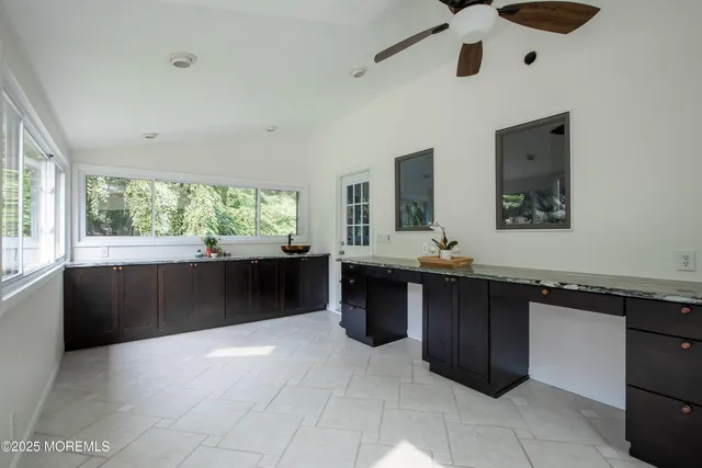 a large kitchen with a large counter top a sink a window and wooden floor