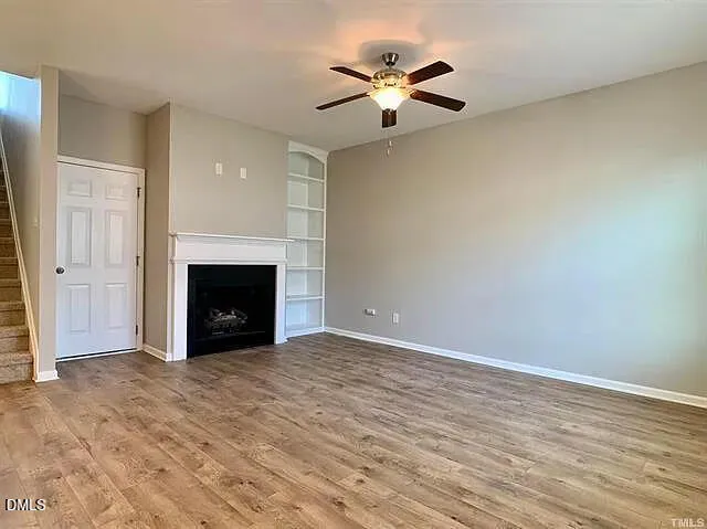 an empty room with a fireplace and a ceiling fan