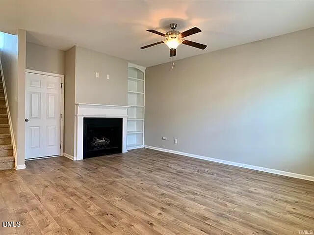134 West Lumber Court Clayton, NC 27520 - Photo 2 of 23 an empty room with a fireplace and a ceiling fan