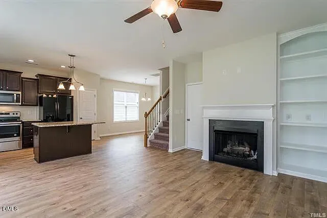 a view of a kitchen and empty room with wooden floor