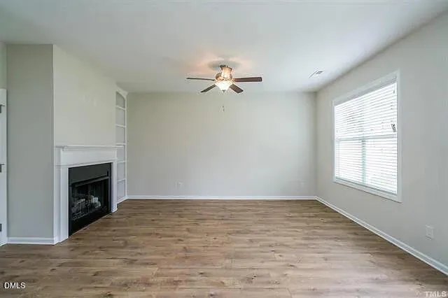 an empty room with chandelier fan and fireplace