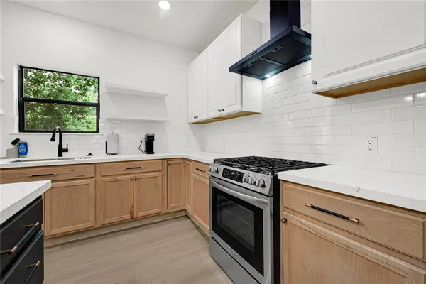 a kitchen with stainless steel appliances a stove a sink and white cabinets