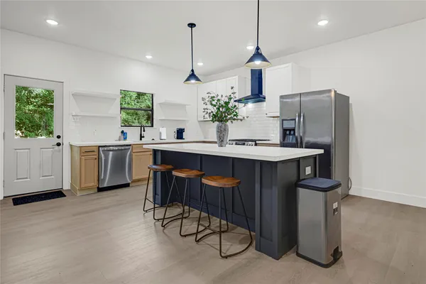 a kitchen with stainless steel appliances kitchen island granite countertop a sink a stove and a refrigerator