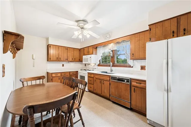 a kitchen with stainless steel appliances granite countertop a refrigerator a sink a stove a dining table and chairs