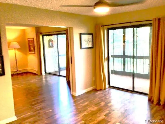 a view of empty room with wooden floor and fan