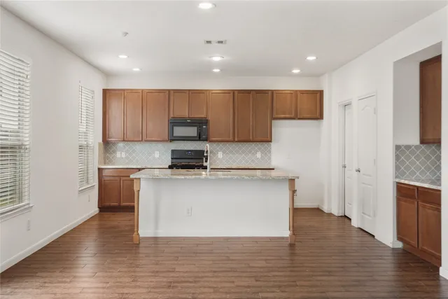 a kitchen with stainless steel appliances granite countertop a stove top oven a sink and a refrigerator