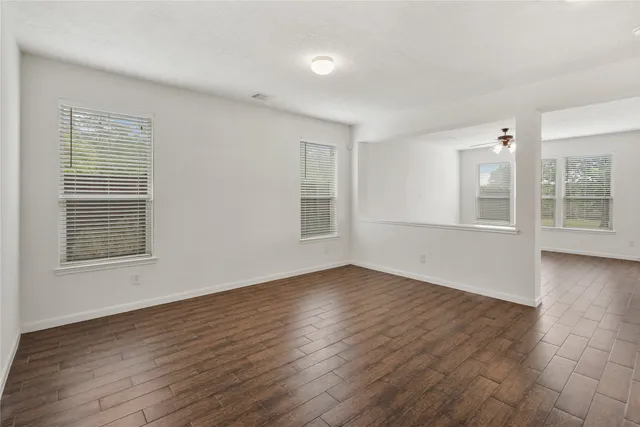 a view of an empty room with wooden floor and a window