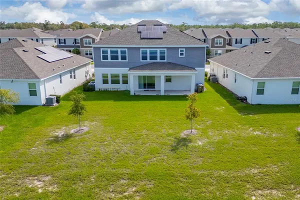 a view of a brick house with a big yard and a large tree